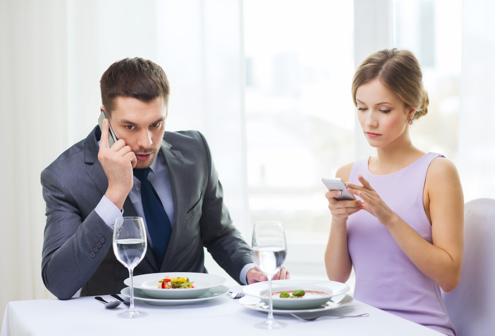 restaurant, couple, technology and holiday concept - busy couple
