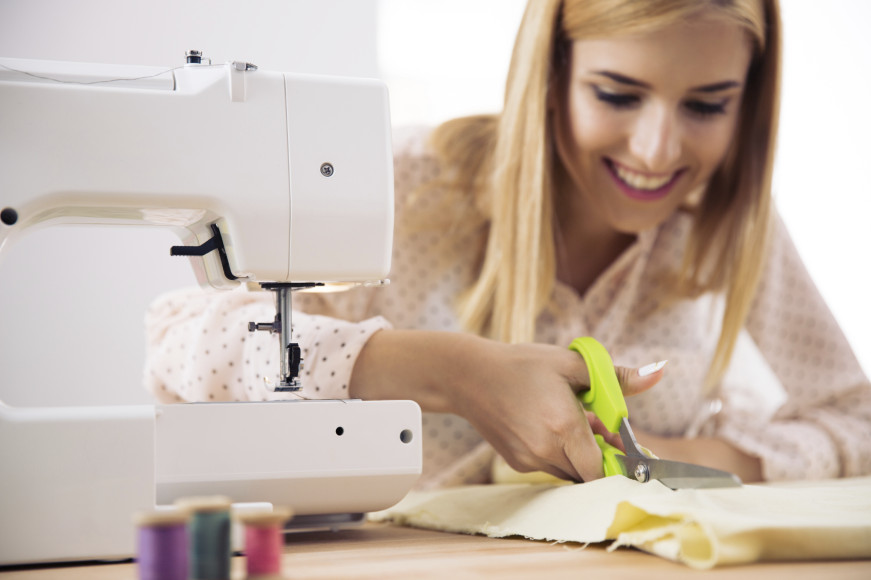 Smiling female designer cutting cloth
