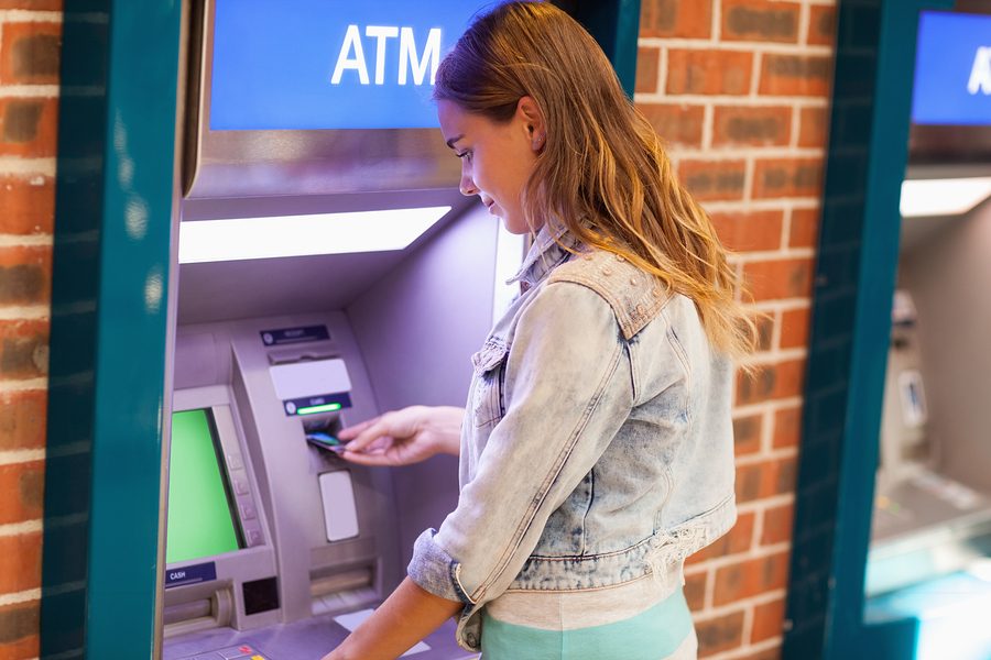 Pretty brunette student withdrawing cash at an ATM